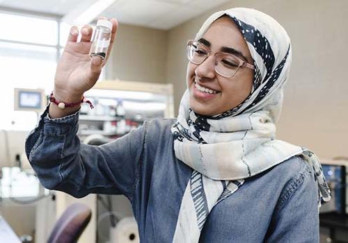 International student in the lab holding a small jar