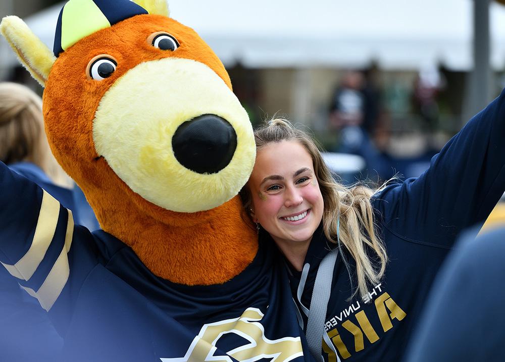 Excited University of Akron student hanging out with Zippy on campus.